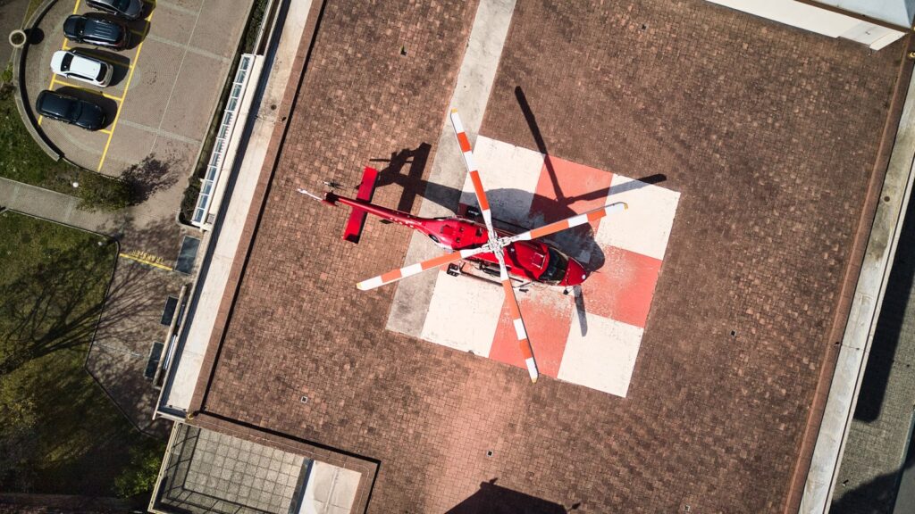 Red helicopter lands on a helipad.