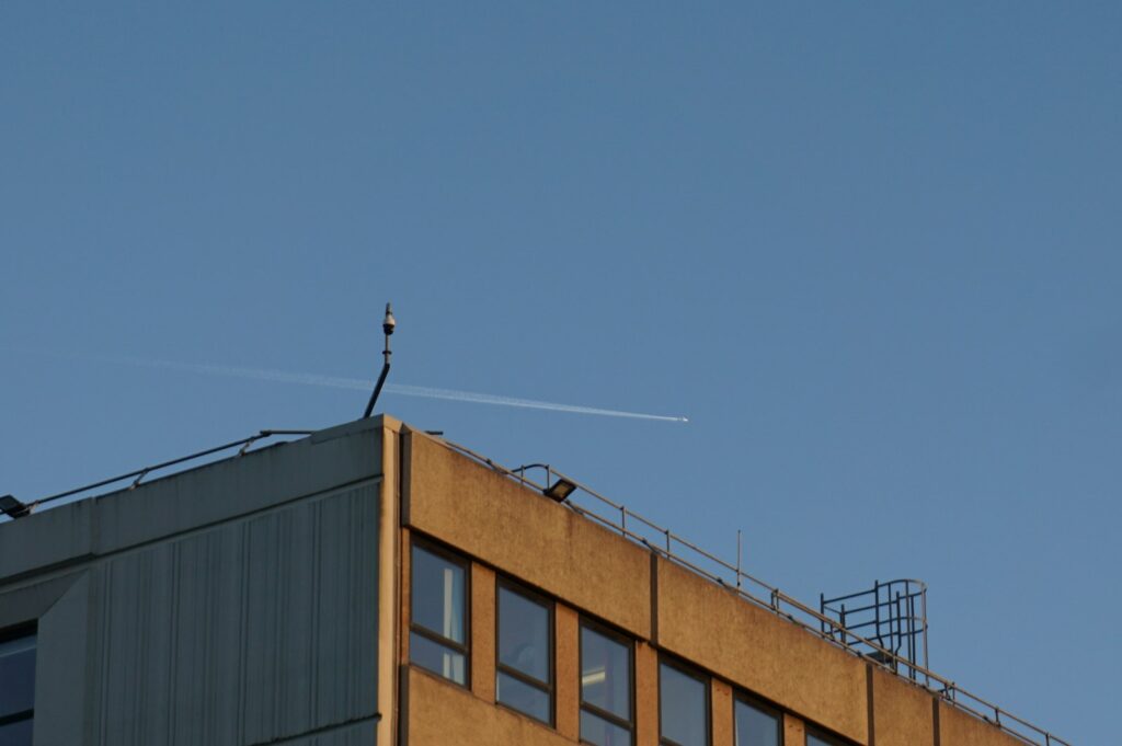 An airplane leaves a contrail across a clear blue sky.