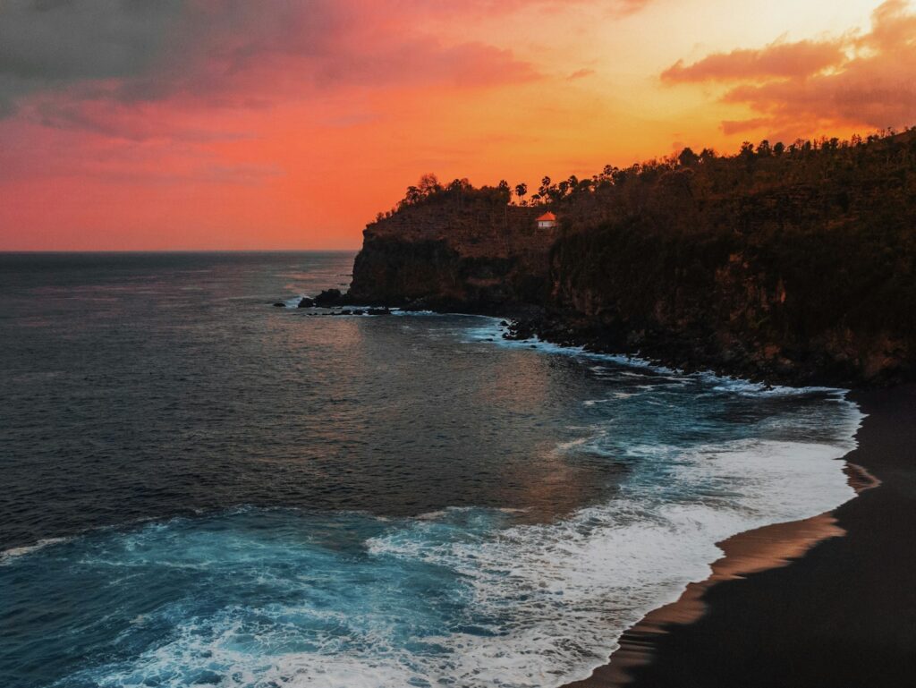 A sunset over the ocean with waves crashing on the shore